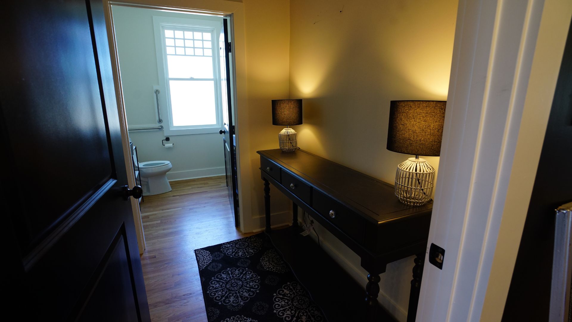 Hallway vanity nook with dark wood console table and lamps near restroom, 521 N McDuffie Workspace
